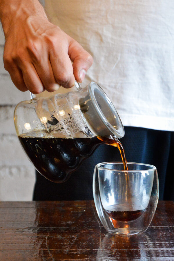 jarra com café sendo despejado no copo de vidro
